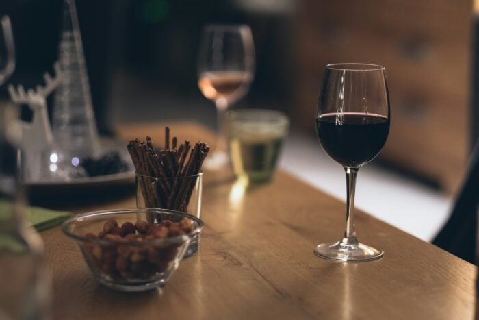 Schwarze Flüssigkeit im klaren Weinglas auf braunem Holztisch - Jessy Smith (@jessysmith)